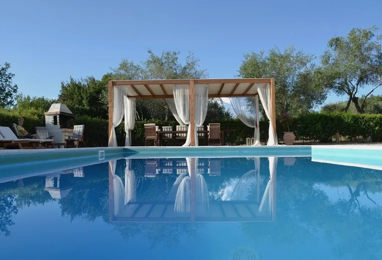 A pool in front of a garden pergola